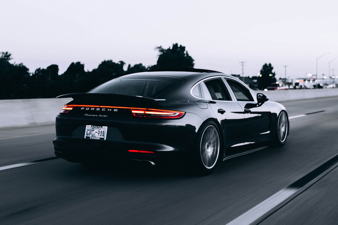Чёрный Porsche Panamera в движении на трассе в сумерках